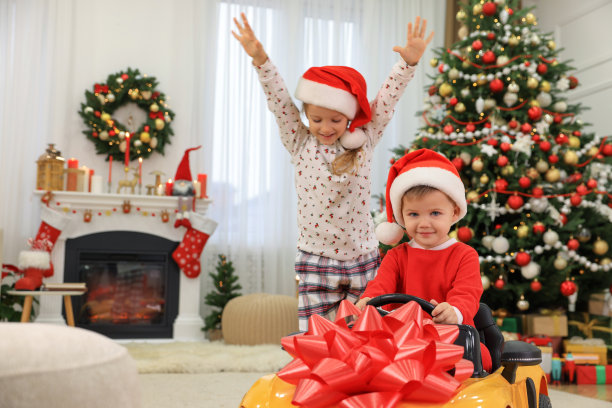 可爱的小朋友在为圣诞节装饰的房间里玩玩具车图片下载