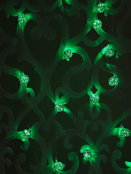 绿色藤球圣诞灯花环在黑暗的背景。圣诞节或新年的绿色灯花环在图案墙上。模糊发光的灯泡花环。垂直的照片。图片下载