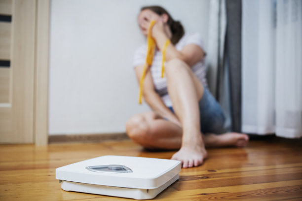 白色的刻度和沮丧，不安和悲伤的女人用卷尺在木地板上图片下载