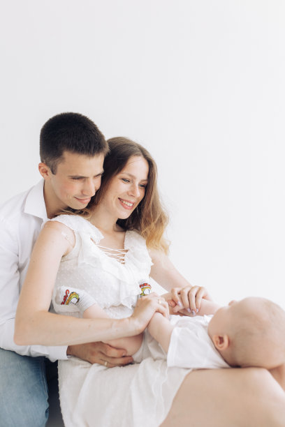 快乐的父母和他们的小男孩坐在一起玩耍。图片下载