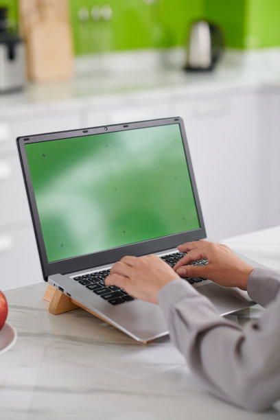 绿色屏幕的笔记本电脑和手的现代自由职业者或设计师的键盘图片下载