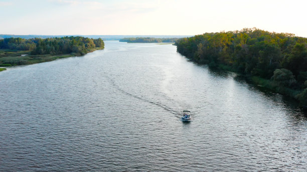 无人机在河上拍摄的照片，日落时一艘缓慢漂流的快艇和船上的人。夏季驾驶汽艇在湖面上的鸟瞰图。图片下载