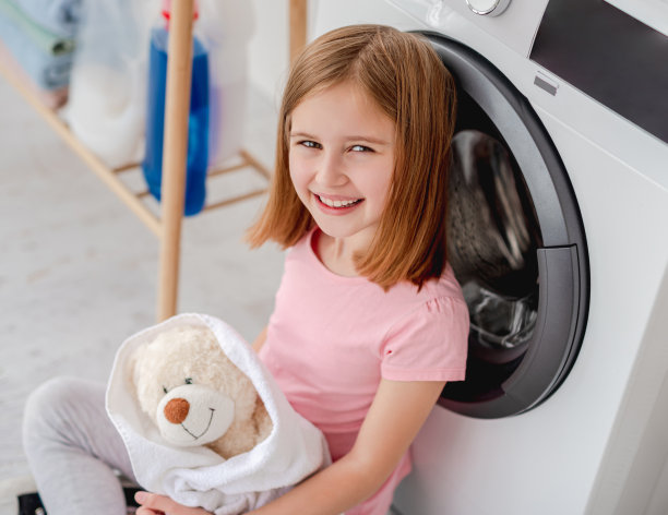 小女孩洗完衣服后抱着泰迪熊图片下载