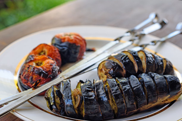 美味的烤肉串和烤蔬菜放在盘子上的桌子图片下载