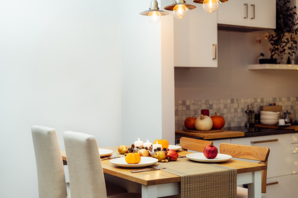 感恩节家庭聚会的秋季餐桌摆设。用蜡烛、水果、坚果和球果组成的秋天。装着南瓜和石榴的盘子。自然秋天装饰。有选择性的重点图片下载