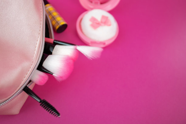 套装化妆品，化妆刷，口红，腮红在化妆袋上一个粉红色的背景，复制空间图片下载