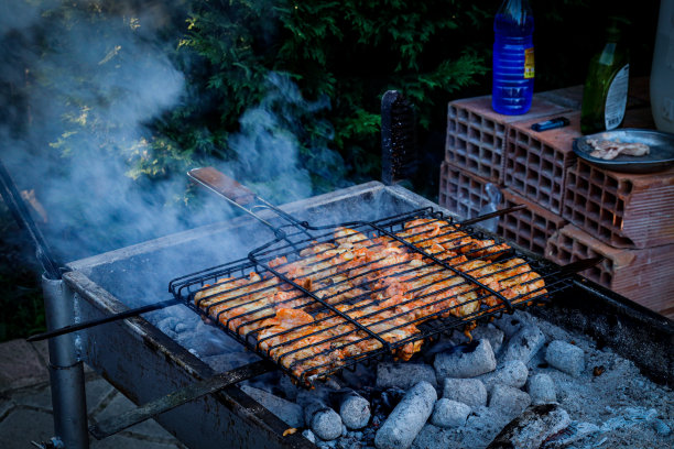 烤鸡翅。在森林里烧烤。用烤架在桶上烤鸡。野餐时在篝火上烤鸡图片下载