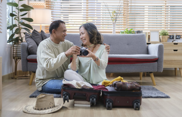 幸福的退休夫妇为度假旅行准备手提箱。退休后的活动，家庭度假的概念。图片下载