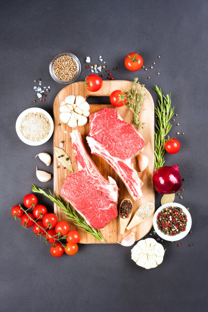 生肋眼牛排与调味木砧板在黑暗的混凝土背景。牛仔带骨牛排可以烤了。查看上图，垂直图像图片下载