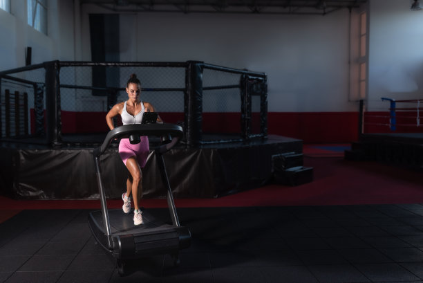 年轻，出汗，活跃，强壮的健身女性在跑步机上跑步或跑步机锻炼，进行有氧训练。女运动员在体育馆里的器械上练习。图片下载