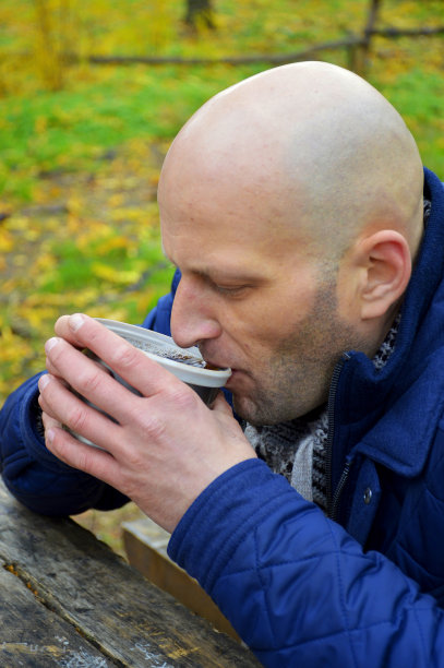 坐在秋天的公园里喝茶或喝咖啡的年轻人图片下载