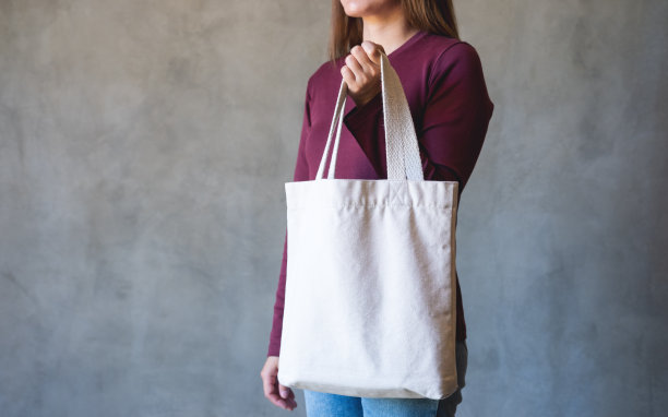 特写图像的年轻女子拿着和携带一个白色织物手提袋可重复使用和环保的概念图片下载