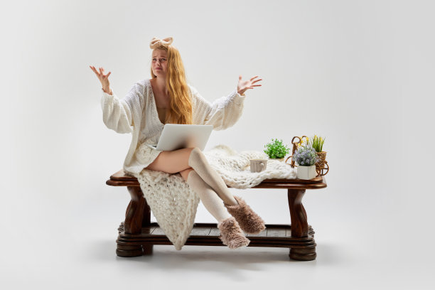 绝望。年轻美丽的女孩坐在木桌和使用笔记本电脑孤立的灰色背景。想法、灵感、想象。复古,复古风格图片下载