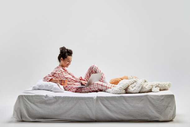 肖像年轻迷人的女孩在家居服坐在床上孤立在灰色的背景。想法、灵感、想象。艺术、美丽、青春图片下载