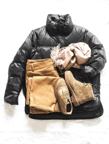 女性季节性冬秋服装-黑色羽绒服，灯芯绒裤子，麂皮靴和羊绒围巾在浅背景，俯视图图片下载