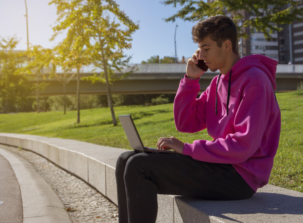 年轻人坐在台阶上，用着笔记本电脑，看着屏幕。图片下载