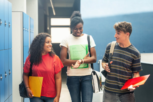 三个十几岁的学生朋友走在大学走廊上图片下载
