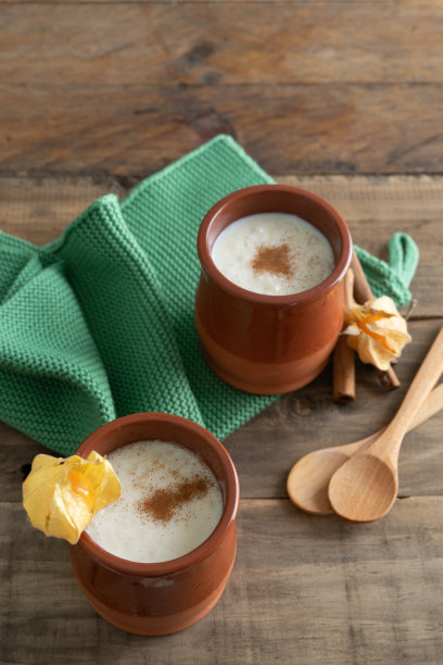 一碗碗的米饭布丁和肉桂放在木制的背景上。副本的空间。垂直的照片。图片下载