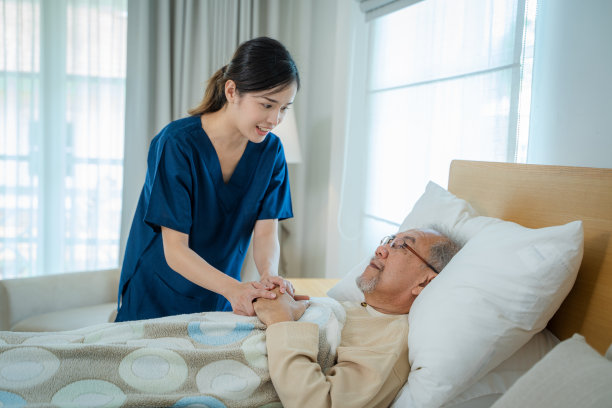 护理人员牵着老年男性患者的手给予安慰。图片下载