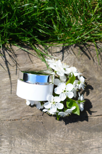 瓶瓶罐罐的化妆品霜、凝胶或乳液，以大自然和花朵为背景。介绍化妆品的背景。空白标签的品牌模型。皮肤护理的概念图片下载