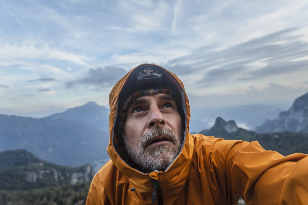 穿着雨衣的徒步旅行者在山上仰望天空图片下载