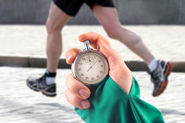 用机械秒表测量运动员的跑步速度。手与秒表的背景上的腿一个跑步者图片下载