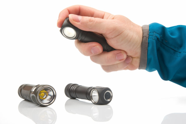 在白色背景的其他手电筒的背景下，手拿着手电筒。露营和家居用品。图片下载