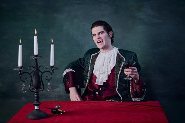 吸血鬼形象中的恐怖男子肖像，德古拉上升的玻璃血在深绿色的背景。咧着嘴笑图片下载