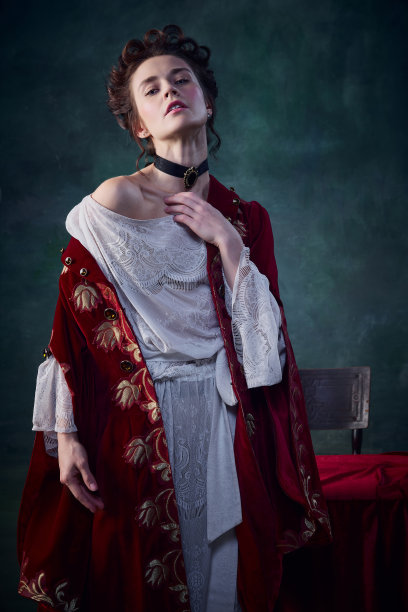 画像年轻神奇的女人与苍白的皮肤在中世纪连衣裙摆姿势在深绿色的背景。吸血鬼的传说图片下载