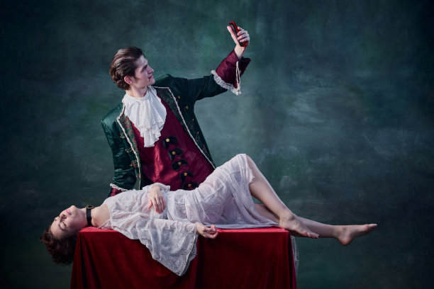 男人的肖像在中世纪吸血鬼的形象自拍的死去的女人躺在桌子上在深绿色的背景。受害者图片下载