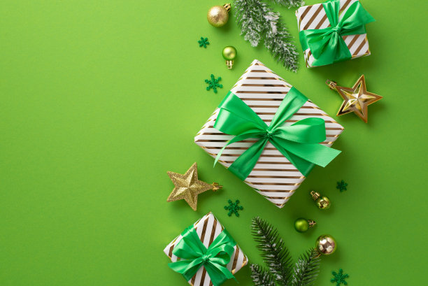 圣诞节的概念。顶视图照片的时尚礼盒丝带蝴蝶结明星饰品金色和绿色的小饰物五彩纸屑和松树树枝在孤立的绿色背景上霜冻图片下载