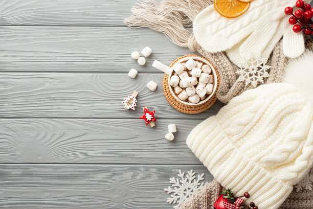 冬天的概念。顶视图照片帽子连指手套格纹杯可可与棉花糖垫装饰夹雪花叮当铃荚木和干橙片在灰色木制书桌背景图片下载