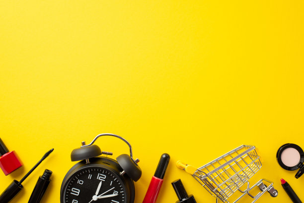 黑色星期五的销售概念。顶视图照片的购物车闹钟化妆品睫毛膏眼影指甲油和唇彩在孤立的黄色背景与copyspace图片下载