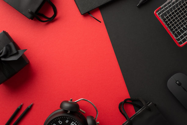 “黑色星期五”的概念。顶视图照片电脑鼠标礼盒与弓购物车闹钟纸袋笔记本和铅笔双色红和黑色背景与中间的copyspace图片下载