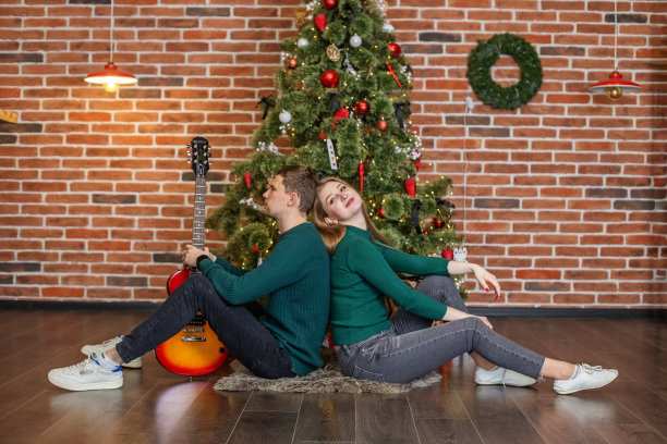 男人和女人一起庆祝圣诞节。男人弹吉他，为女人唱歌。图片下载