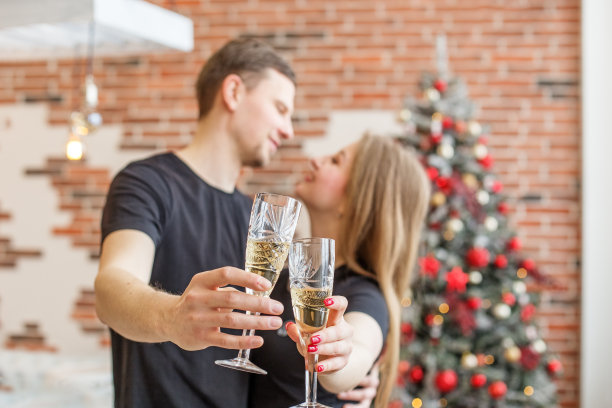 干杯!两个人在圣诞节拿着香槟酒。夫妻二人一起庆祝新年图片下载
