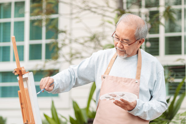 长者在画布上作画，老人在后院里作画。资深成熟艺术家手持彩色油画画在白纸上。老年人活动。快乐的老人。生活方式和退休理念。图片下载
