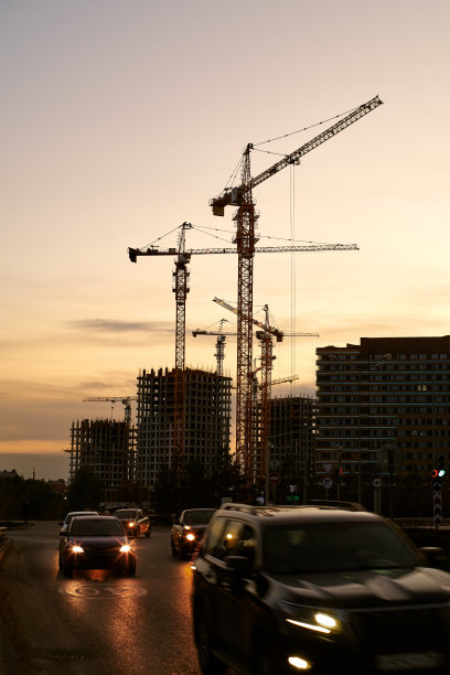 在黄桔色的天空下，建筑工地的塔吊和建筑轮廓图片下载