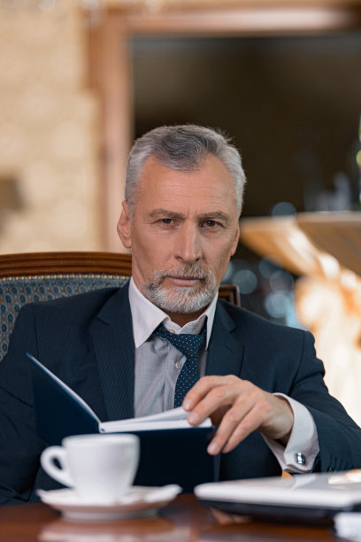 坐在豪华酒店房间里的商人一边看日记一边喝咖啡图片下载