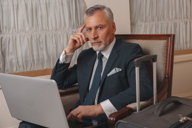 商人坐在酒店大厅里用笔记本电脑工作，等待办理入住手续图片下载