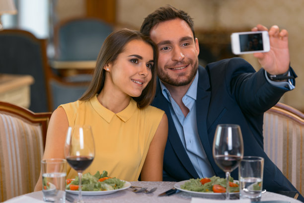 年轻夫妇在昂贵的酒店吃浪漫的晚餐，用手机自拍图片下载