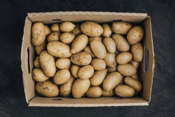 土豆。新鲜的有机土豆在黑色的石头背景的纸盒。图片下载