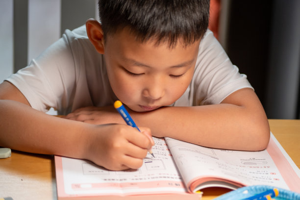 一个亚洲男孩正在家里做作业图片下载