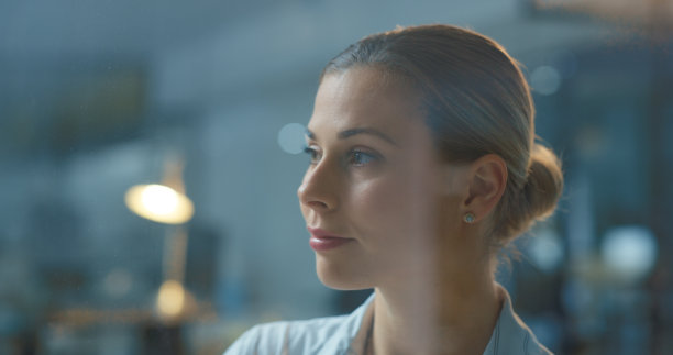 思考，梦想和目标，一个女商人望着窗外的想法，愿景和使命站在办公室的夜晚。德国女员工的脸看起来深思熟虑，寻找灵感图片下载