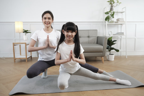 亚裔泰国母亲和女儿一起在客厅地板上练习瑜伽。图片下载