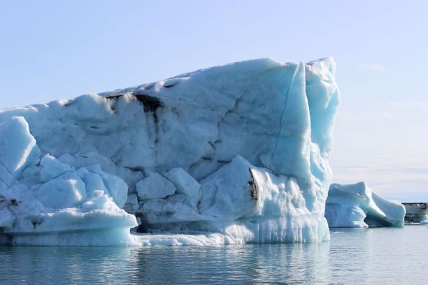 在一个阳光明媚的日子里，冰山在海洋中央图片下载