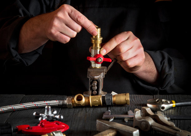 水管工在修理设备时连接黄铜配件。师傅在车间工作时的手特写图片下载
