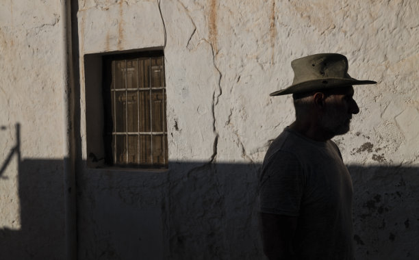 成年男子肖像在牛仔帽对墙与阳光和阴影图片下载