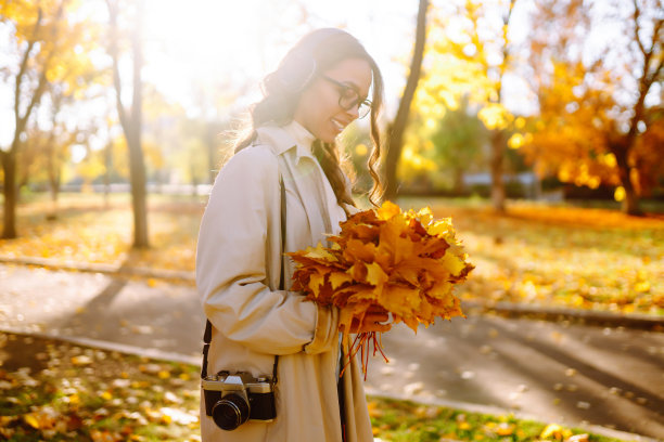 在秋天的森林里拍照的年轻女子。图片下载