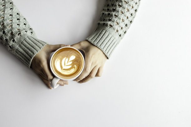 女人的手拿着杯与咖啡在白色的桌子背景，俯视图图片下载